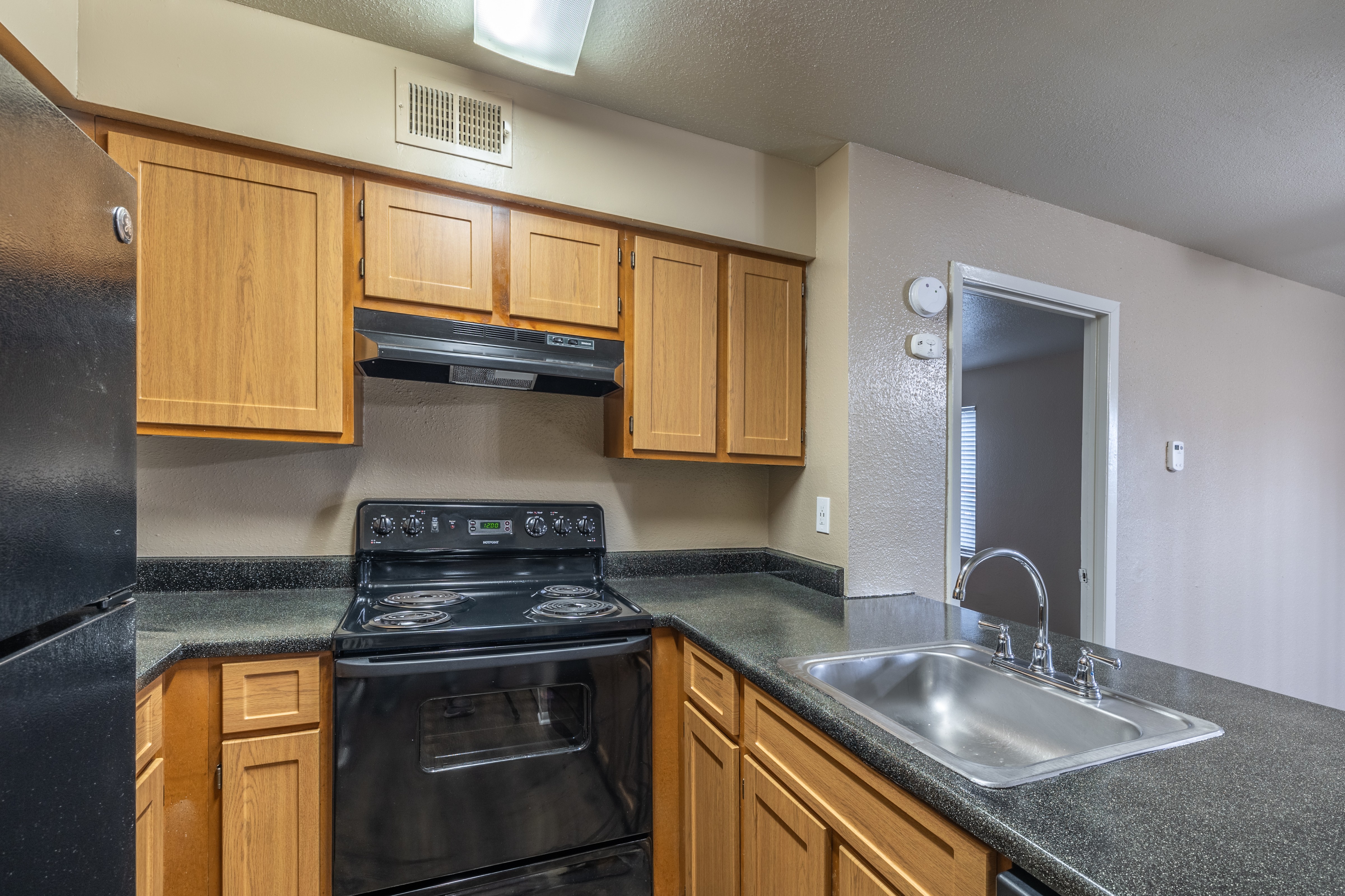 A kitchen with black appliances and wooden cabinets.